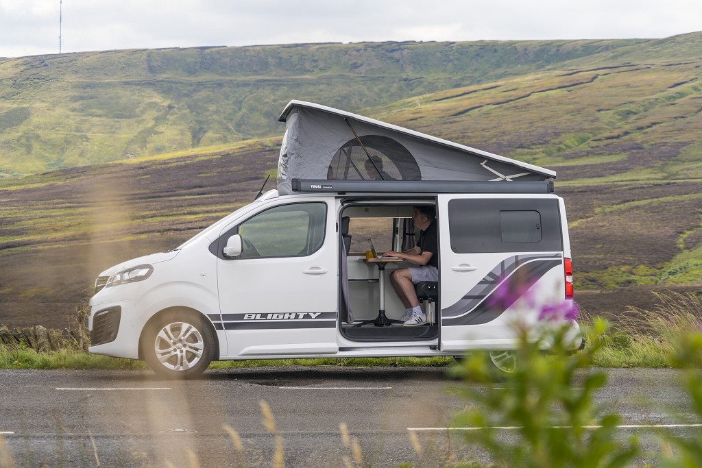 Furgoneta camper con techo elevable abierto junto a la carretera