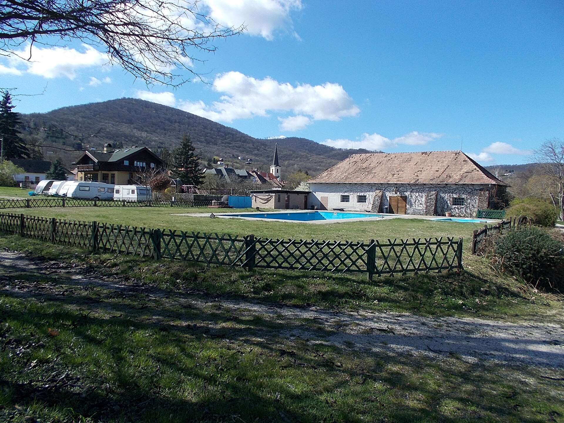 Piscina y parcelas de un camping con montañas al fondo