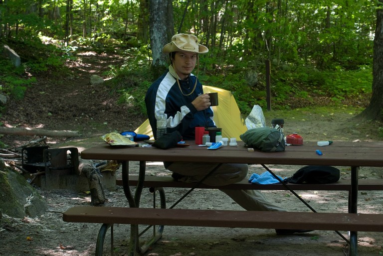 Zona de cocina en una parcela de camping con el hornillo sobre la mesa
