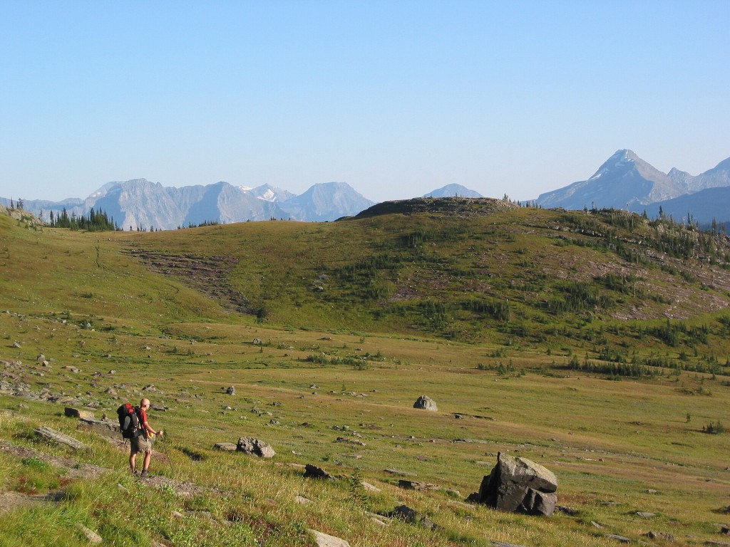 Senderista con mochila de travesía en una pradera de montaña