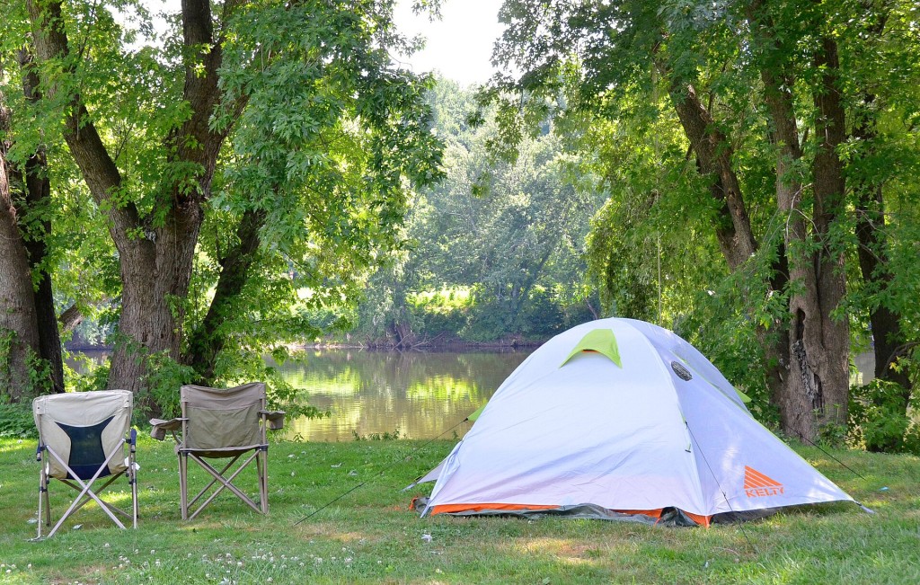 Dos sillas de camping junto a una tienda a la orilla de un río