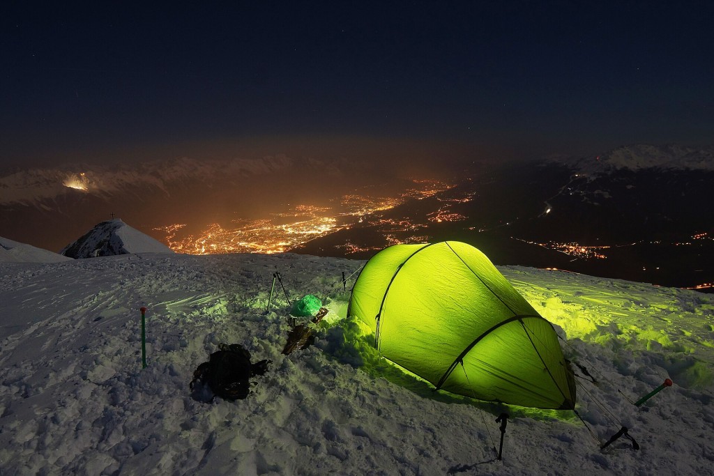 Tienda de campaña iluminada sobre la nieve de noche